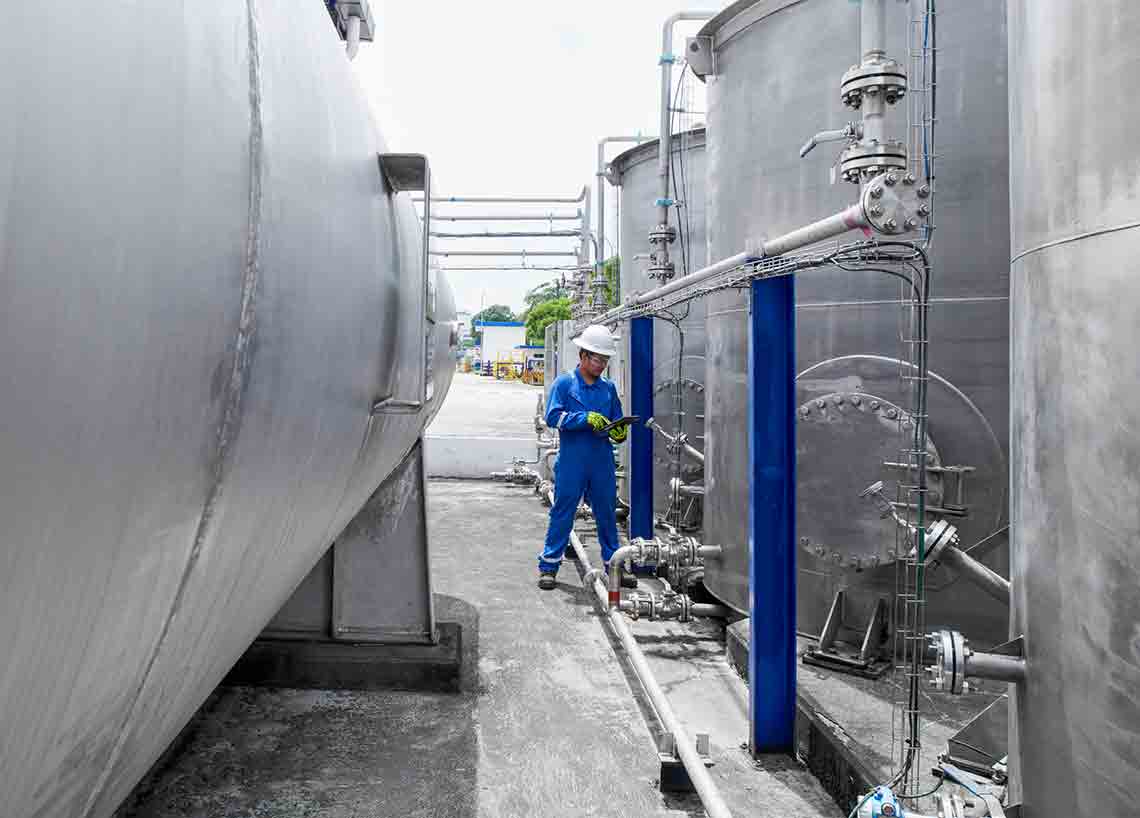 Photo of an in blue coveralls monitoring tanks (Tier 1_ManufacturingFacility_Singapore_ASIA_15896)